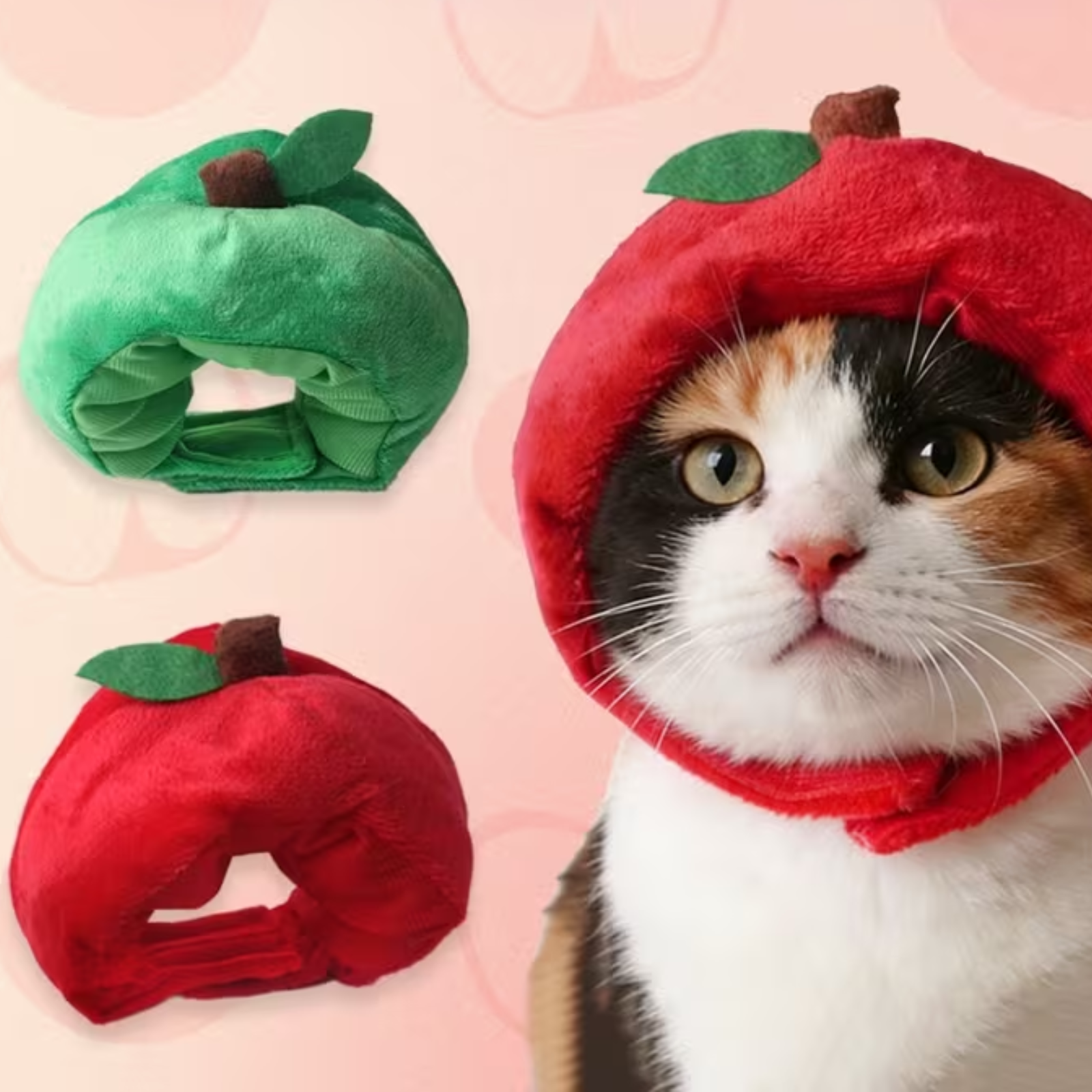 A calico cat wearing a red apple-shaped pet hood with a green leaf, shown alongside two smaller views of the same hood in red and green on a pale pink background.