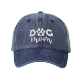 A washed navy blue baseball cap featuring white embroidered text that reads 'DOG mom' with a paw print icon inside the letter O, shown against a plain white background.