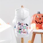 White dog hoodie with colorful 'Too Cute To Spook' text and Halloween graphics on a mannequin, with pumpkins and candles in the background.