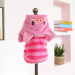 A pink plush pig hooded coat displayed on a stand against a softly blurred indoor background with shelves and a plant.