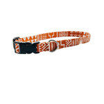 A dark orange and white patterned dog collar with a black plastic buckle and a silver metal ring, shown on a plain white background.