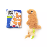 A plush dinosaur-shaped dog toy in tan faux fur with a green curly tail, shown next to its blue packaging bag labeled 'Dino Snacks'.
