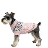 Dog wearing a pink knitted sweater with a pattern on a white background