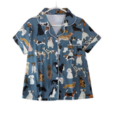 A short-sleeve pajama shirt with a blue-gray base and an all-over print of various dog illustrations, shown hanging against a plain white background.