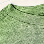 Close-up of a green heathered knit fabric, showing the ribbed crew neck and fine texture.