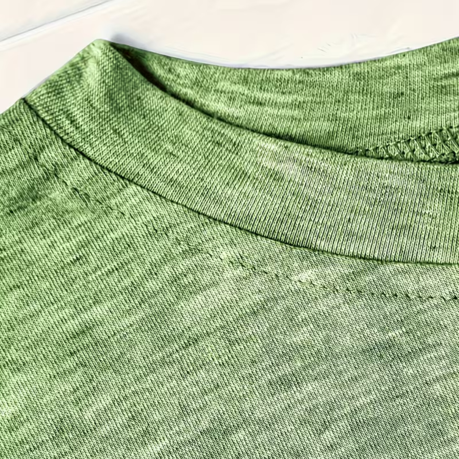 Close-up of a green heathered knit fabric, showing the ribbed crew neck and fine texture.