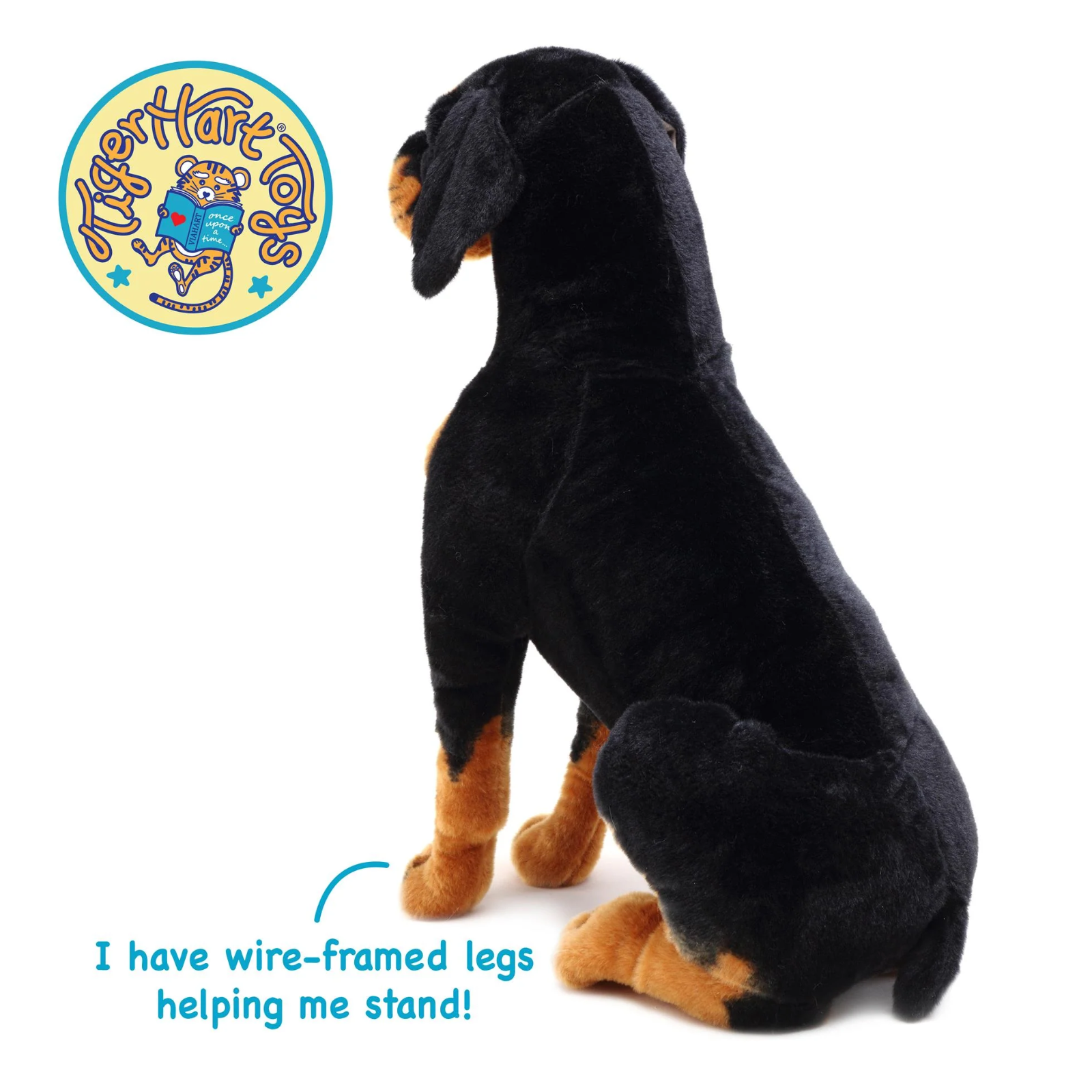 A black and tan plush dog toy shown from the back on a white background, with a circular TigerHart Toys logo in the top-left and text at the bottom stating 'I have wire-framed legs helping me stand!'.