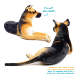 Two plush German Shepherd dog toys shown on a white background, one facing left and one facing right, with blue text reading 'I'm soft and cuddly!' and additional safety text in the lower right.