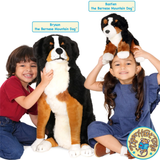 Two children with a large stuffed Bernese Mountain Dog toy and a smaller Bernese Mountain Dog plush toy on a white background.