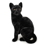 A black plush stuffed animal shaped like a sitting cat with yellow eyes, photographed on a plain white background.