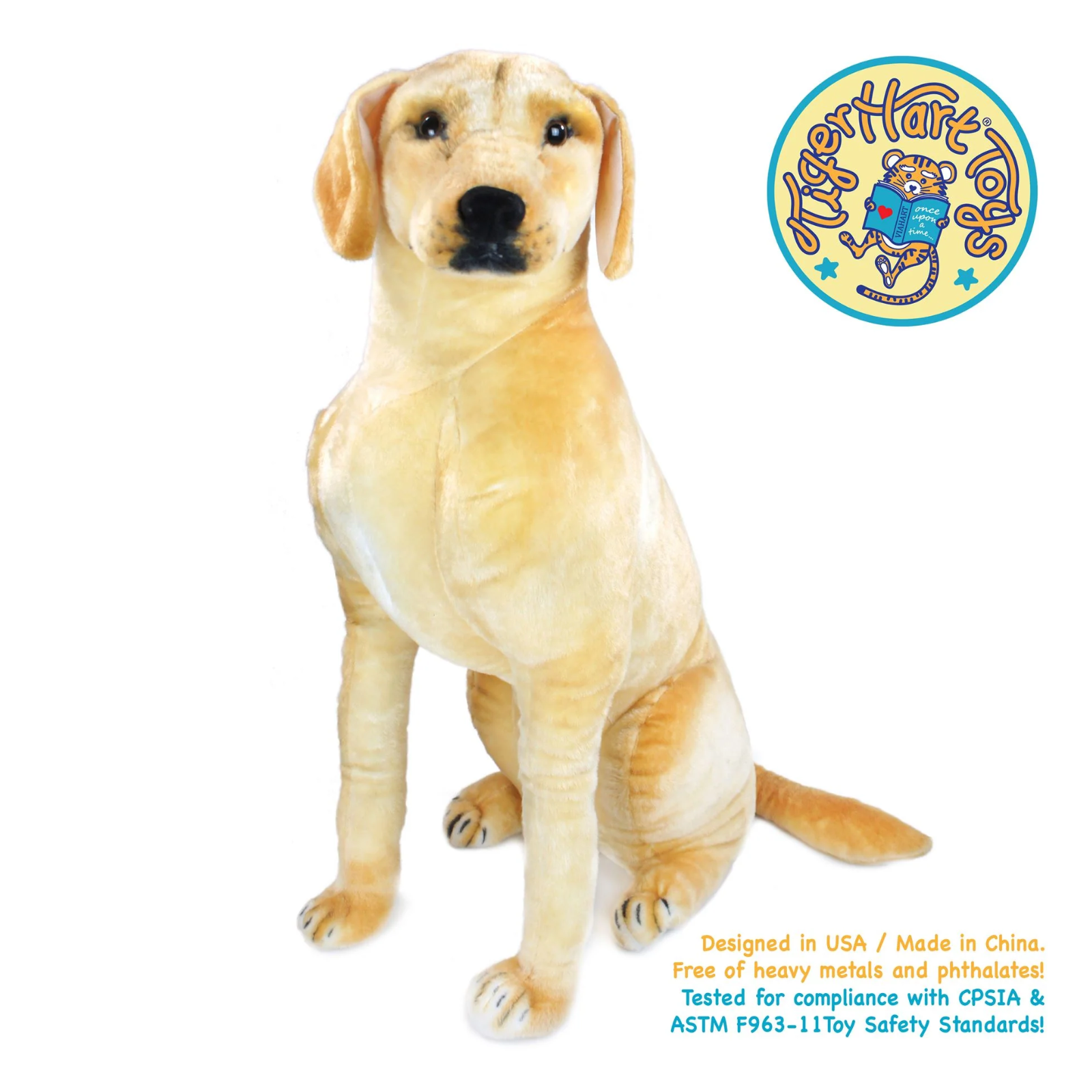 A yellow Labrador retriever plush toy sitting on a white background, with a circular 'Tiger Hart Toys' logo in the top right and text stating 'Designed in USA / Made in China' with other safety text in the bottom right.