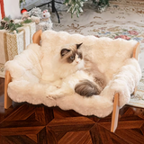 Cat lounging on a fluffy white pet bed in a cozy room with Christmas decorations.