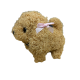 A small curly-fur dog plush toy in light tan with a pink ribbon bow on its back, shown against a plain white background.