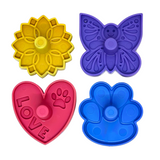 Four colorful plastic treat stoppers shaped like a yellow flower, purple butterfly, pink heart with 'LOVE' and paw print, and a blue paw print, arranged on a white background.