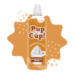 A bottle of Pup Cup! whipped treat for dogs in Peanut Butter Flavor, shown against a white background with a decorative brown-orange splash graphic behind it.