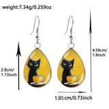 Teardrop-shaped dangle earrings with a black cat and yellow cup illustration, shown with silver fishhook wires and overlaid dimension arrows and text on a white background.