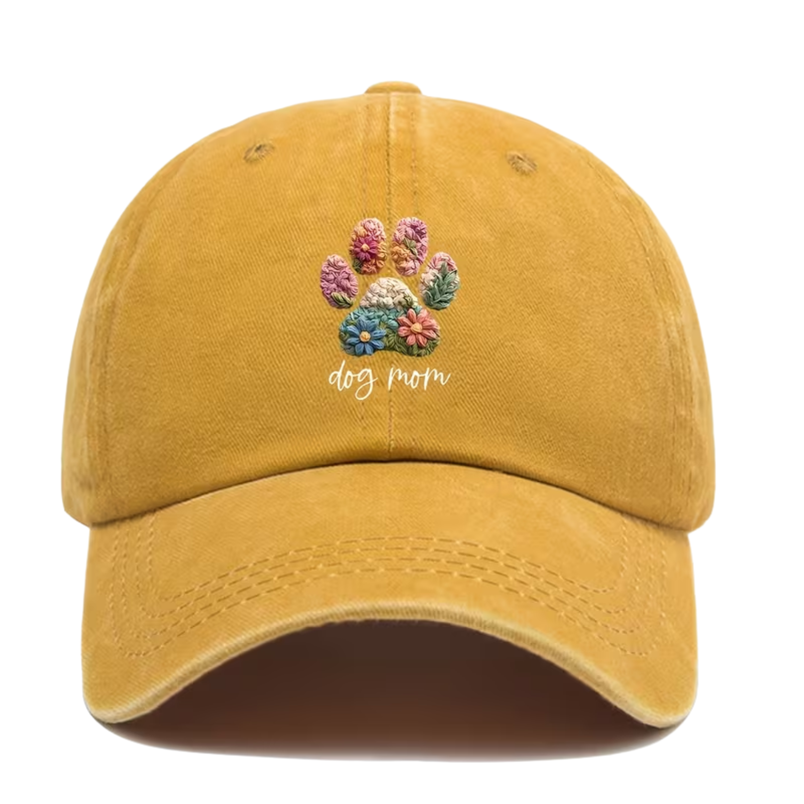 A mustard yellow baseball cap featuring a colorful embroidery-style dog paw print with flowers and the words 'dog mom' in white script on the front. 