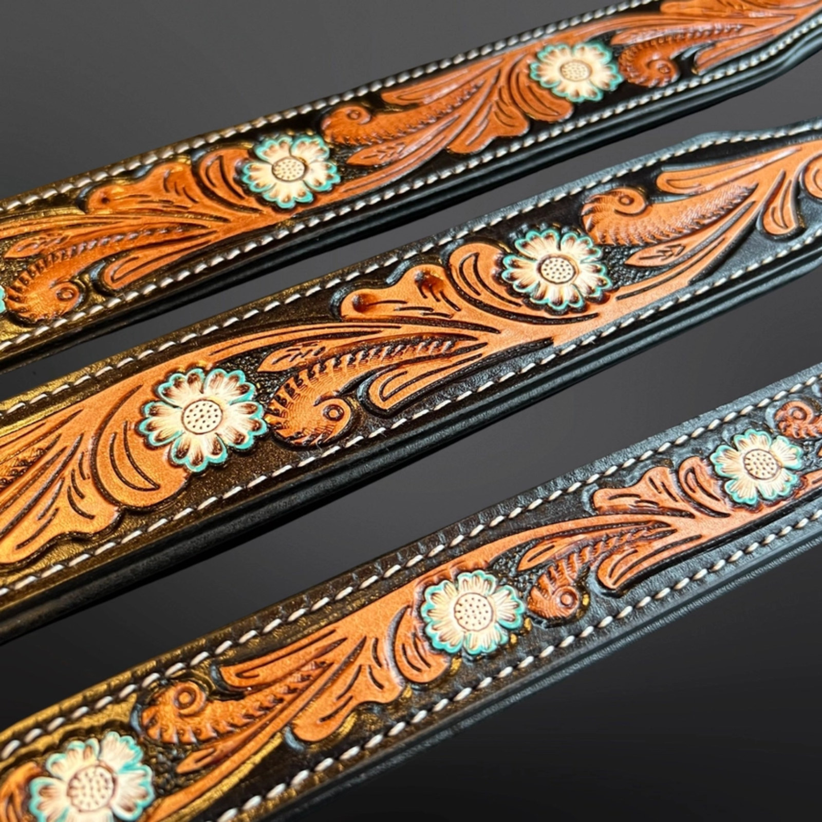 Decorative leather straps with floral patterns on a dark background