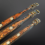 Three tooled leather dog collars with ornate floral designs, displayed diagonally on a dark gradient background.