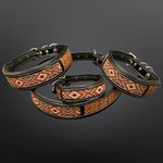 Three black leather dog collars with geometric patterned bands in red, orange, and beige, arranged on a dark gray gradient background.
