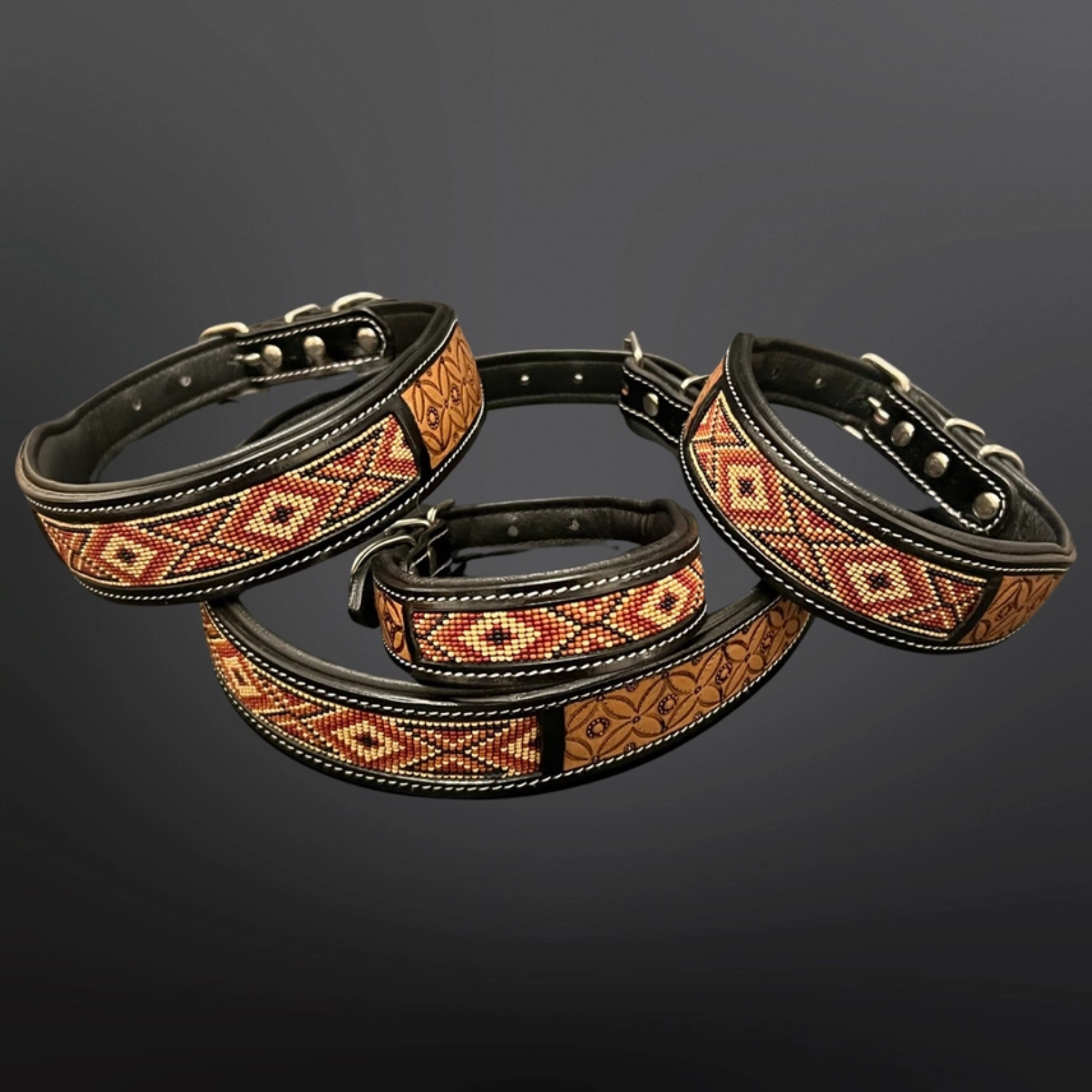 Three black leather dog collars with geometric patterned bands in red, orange, and beige, arranged on a dark gray gradient background.