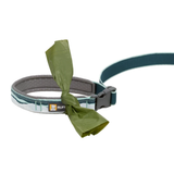 A dark teal and grey leash with a green plastic bag tied around the handle.