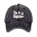 A dark gray washed baseball cap featuring the white text 'The Dogfather' and two paw prints on the front, set against a plain white background.