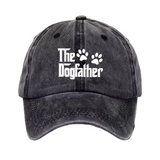 A dark gray washed baseball cap featuring the white text 'The Dogfather' and two paw prints on the front, set against a plain white background.