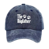 A washed dark blue baseball cap with white text reading 'The Dogfather' and two paw prints on the front, shown against a plain white background.