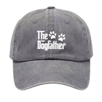 A gray washed baseball cap featuring the white text 'The Dogfather' with two paw prints, shown against a plain white background.