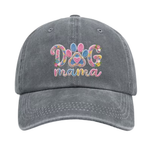 A light gray washed baseball cap featuring a colorful embroidered 'DOG mama' design on the front, with a paw print motif inside the letters, shown against a plain white background.