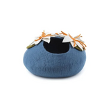 A dark blue felt pet cave with white and orange flowers with green leaves on the top displayed on a white background. 