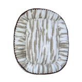 A brown and white textured pet bed with brown leather trim shown from above and displayed on a white background.